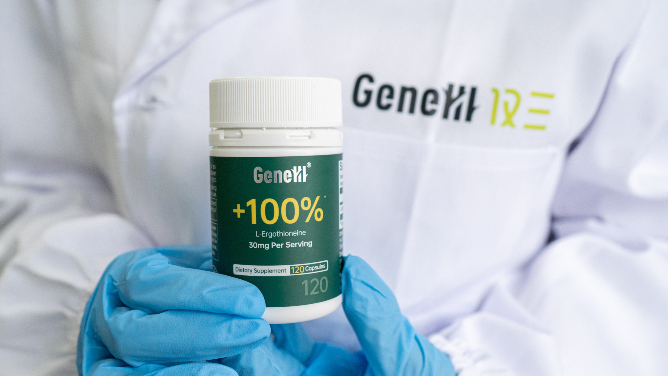 Lab technician in blue nitrile gloves holding a GeneIII L-Ergothioneine 99.99% pure capsule bottle in a clinical laboratory environment, representing third-party HPLC purity testing